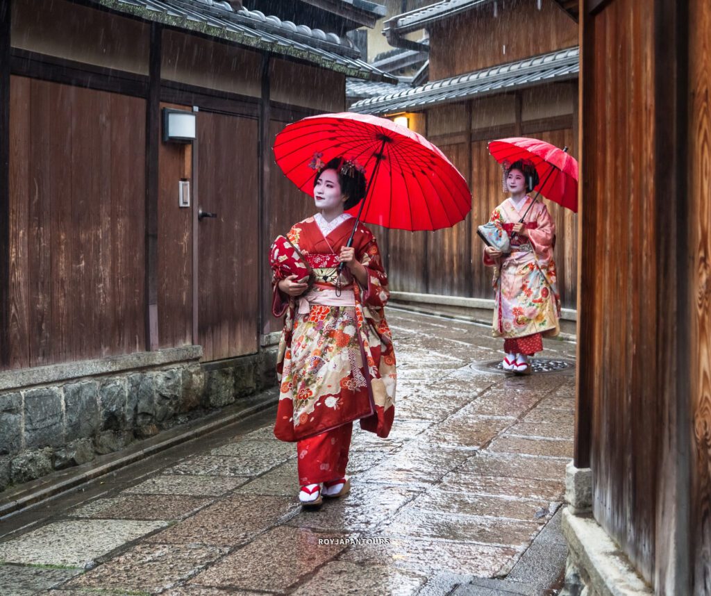 Geisha walking gracefully in traditional attire under the rain in Japan