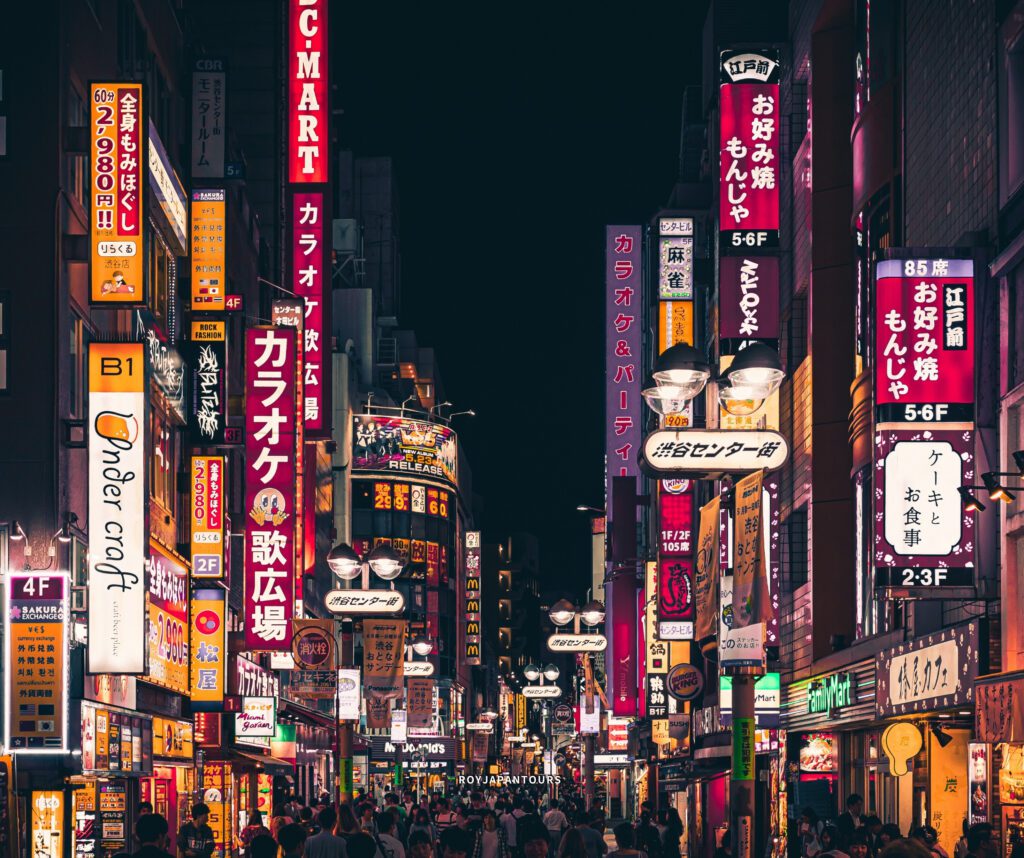 People walking past open restaurants and convenience stores on a rainy night in Japan